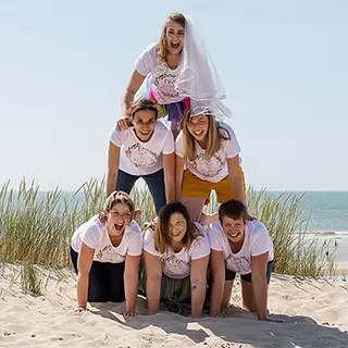 Dans un jeu amusant et un esprit d'équipe, un groupe de femmes crée une pyramide humaine sur le sable, symbolisant leur solidarité et leur amusement partagé.