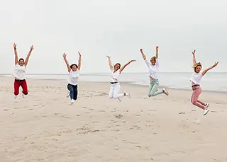 Capturant un moment de liberté insouciante, des femmes sautent dans les airs sur la plage, leurs sourires aussi larges que leurs mouvements.