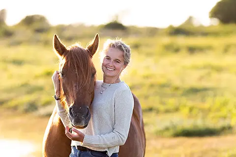 Galop sur la plage Une femme et son cheval posent dans un paysage verdoyant au coucher du soleil