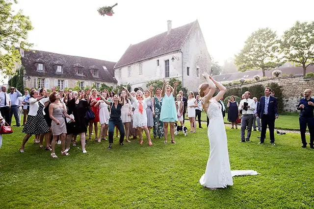 La mariée lance le bouquet au traditionnel lancé de bouquet lors du vin d'honneur