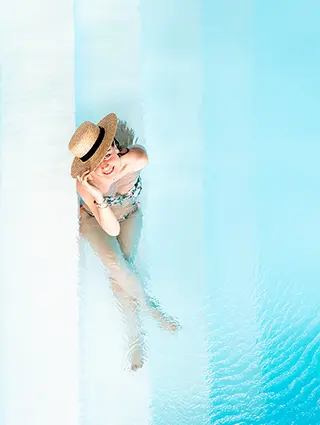 Femme se relaxant avec un chapeau de paille au bord de la piscine